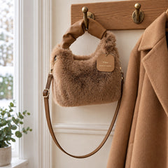The Debbie Faux Fur Shoulder Bag with Top Handle in Brown on a coat hook