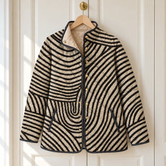 The Lisa Swirl Print Quilted Stand Collar Jacket in Black Cream Swirl on a hanger