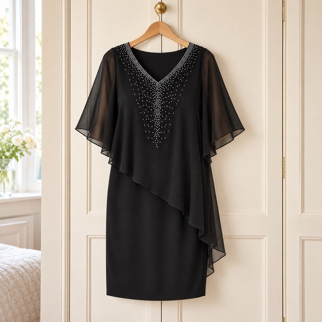 The Philippa Embellished V-Neck Dress with Chiffon Cape Overlay in Black on a hanger